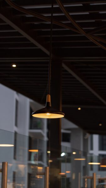 A stylish pendant light hanging in a modern outdoor setting at night, creating a warm ambiance.