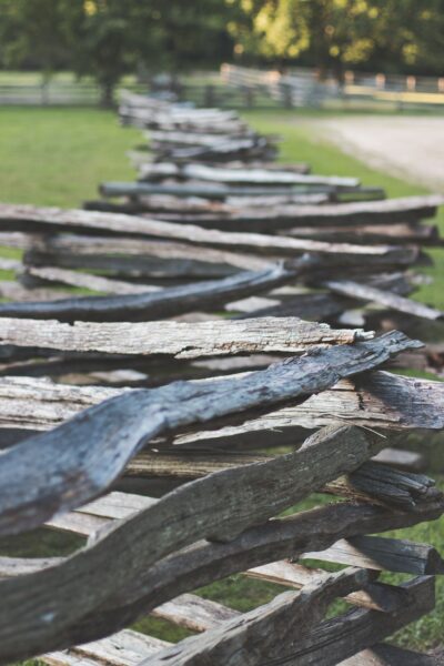 A zigzag split rail fence stretching across a lush rural landscape during the day.
