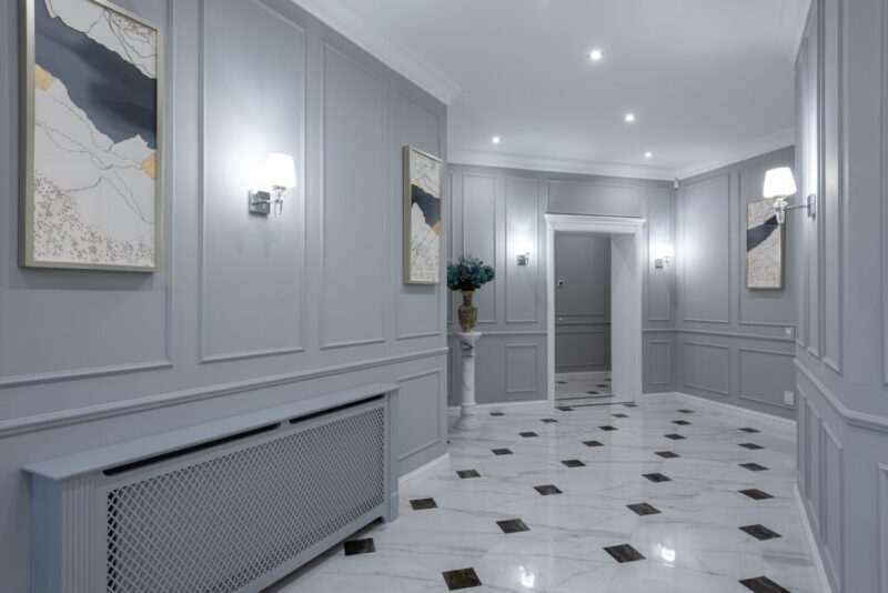 Interior of corridor of contemporary villa with shiny tiled floor and gray walls decorated with paintings and lamps
